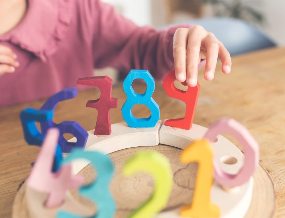 Child placing wooden number decorations in a Grimm's celebration ring, available in Australia from Oskar's Wooden Ark
