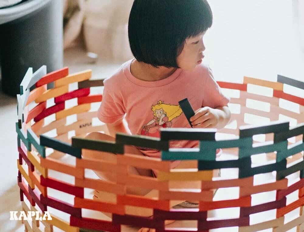 Young child building a rainbow den using KAPLA coloured building planks at Oskar's Wooden Ark in Australia