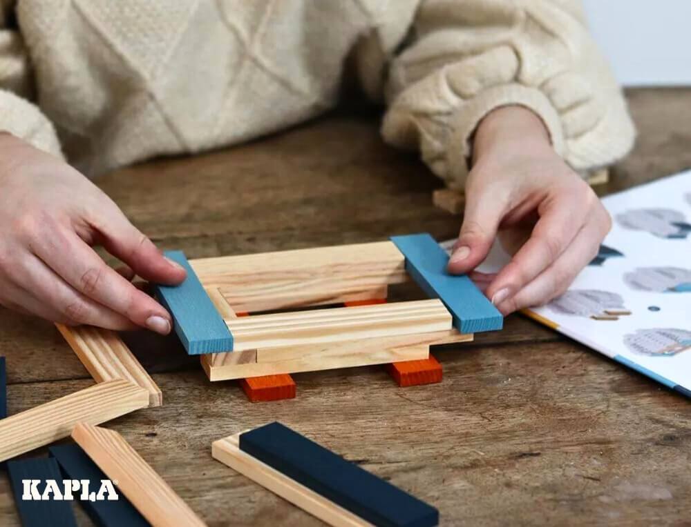 Woman building KAPLA Owl by following guided instructions, using KAPLA construction planks for children and adults, at Oskar's Wooden Ark in Australia 