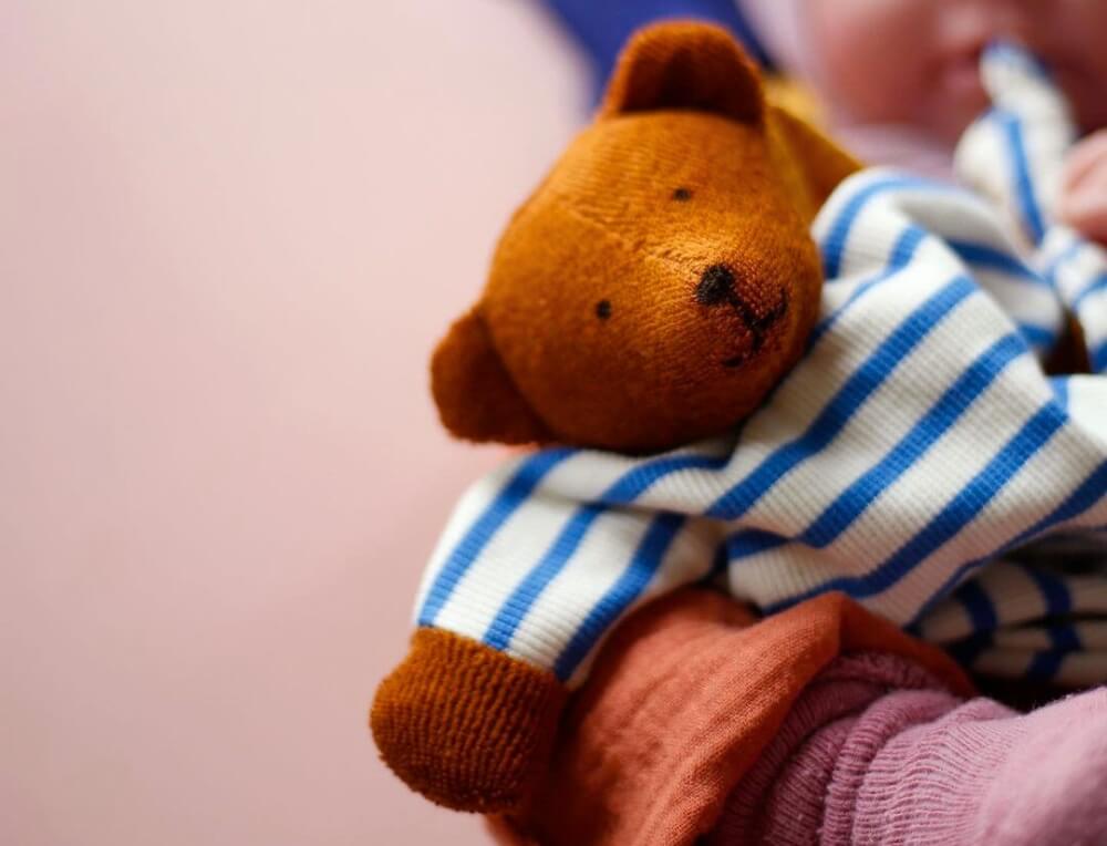 Young baby cuddling a Nanchen Natur soft, organic teddy bear handmade from natural materials, available in Australia from Oskar's Wooden Ark