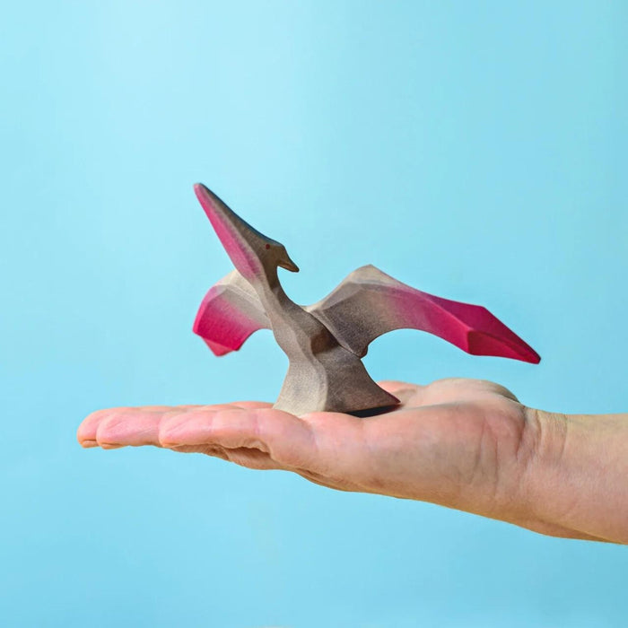 BumbuToys Handcrafted Wooden Dinosaur Pteranodon from Australia on an adult person's palm