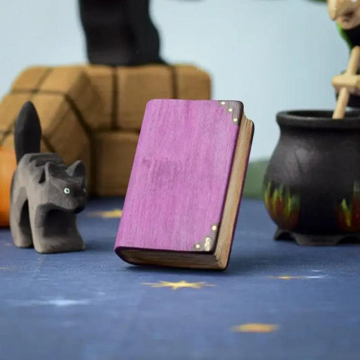 BumbuToys Wooden Purple Book Figurine in Halloween-Inspired Small World Play Scene with Black Scared Cat and Witch's Cauldron in the Background