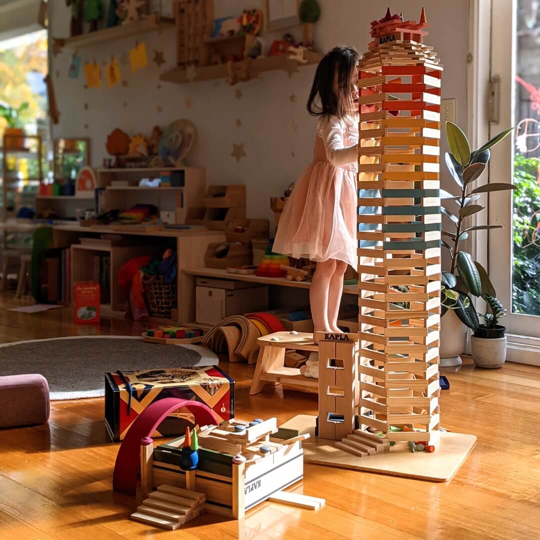 Child building a tall tower with KAPLA construction planks at Oskar's Wooden Ark in Australia