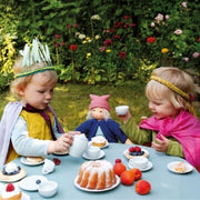 Two children enjoying an imaginative tea party role-play game alongside their Nanchen Natur dress-up doll from Oskar's Wooden Ark in Australia