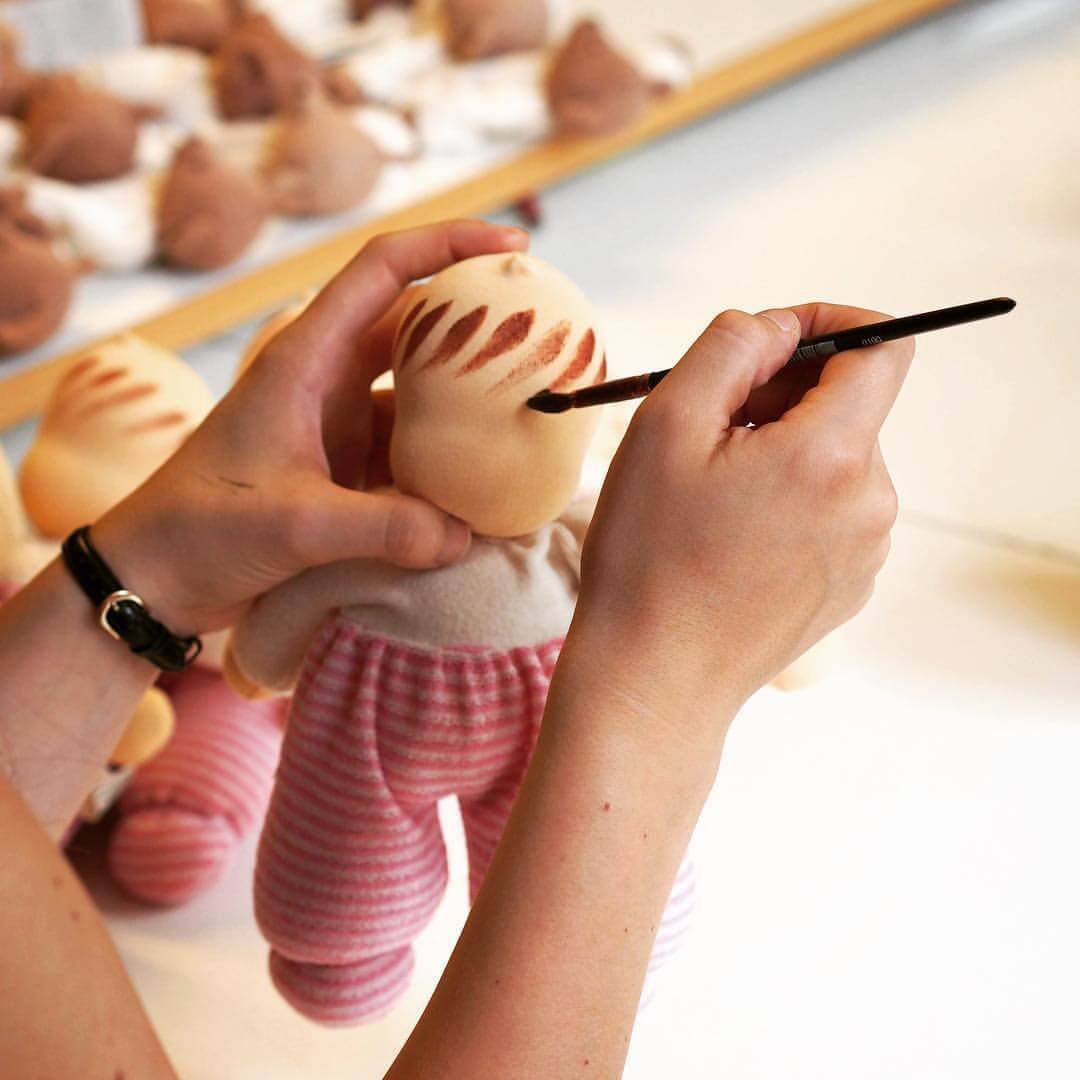 Artisan painting the face of a Nanchen Natur Doll by hand, ensuring a high quality toy for childhood and beyond