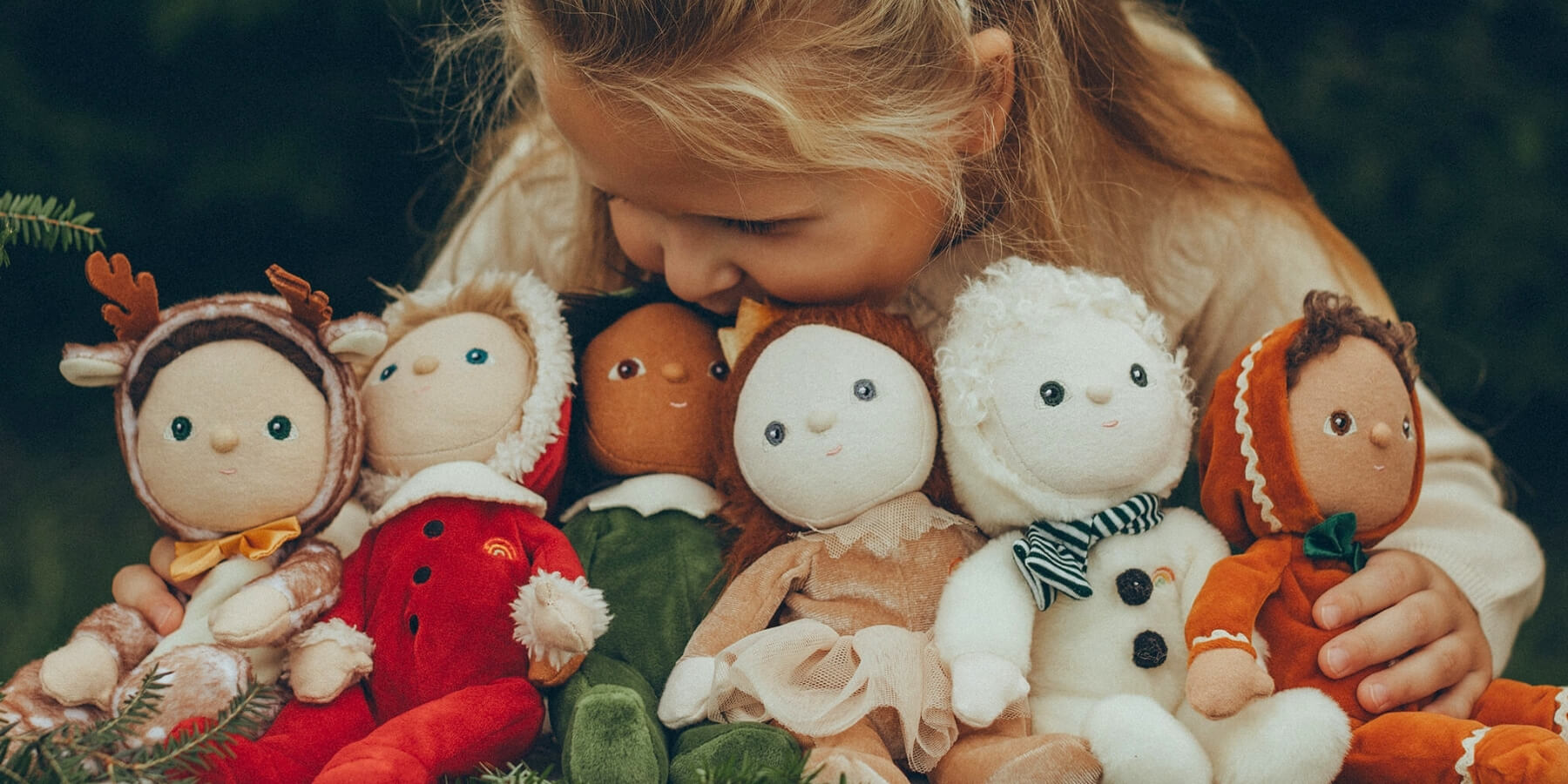 Little girl with her collection of Christmas-themed Olli Ella Jolly Dollies  soft bodied dolls at Oskar's Wooden Ark in Australia