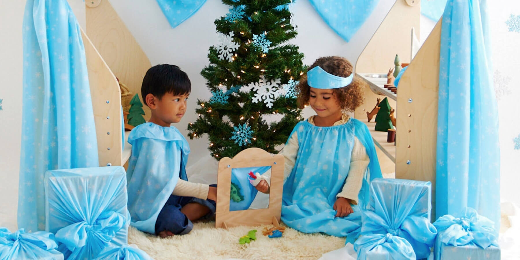 Children playing with little puppet theatre and Christmas snow collection play silks from Sarah's Silks at Oskar's Wooden Ark in Australia