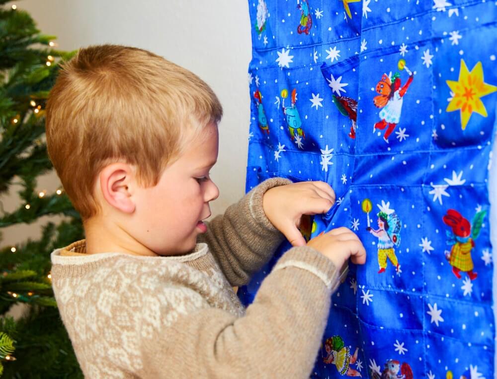 Child revealing little gift inside Sarah's Silks Advent Calendar at Oskar's Wooden Ark in Australia