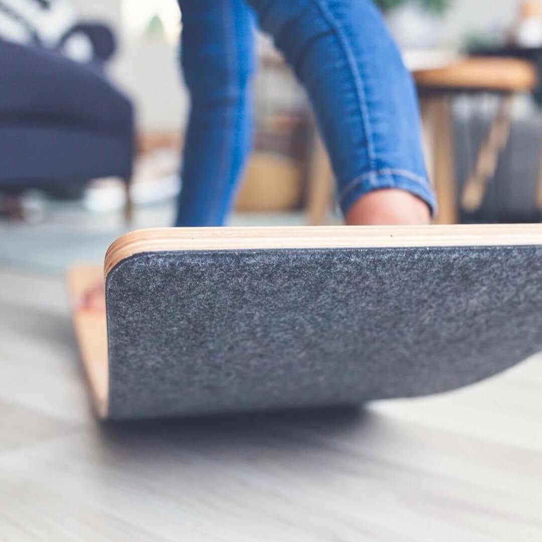 Child rocking on Wobbel Board featuring an all-natural wool felt base, from Oskar's Wooden Ark in Australia