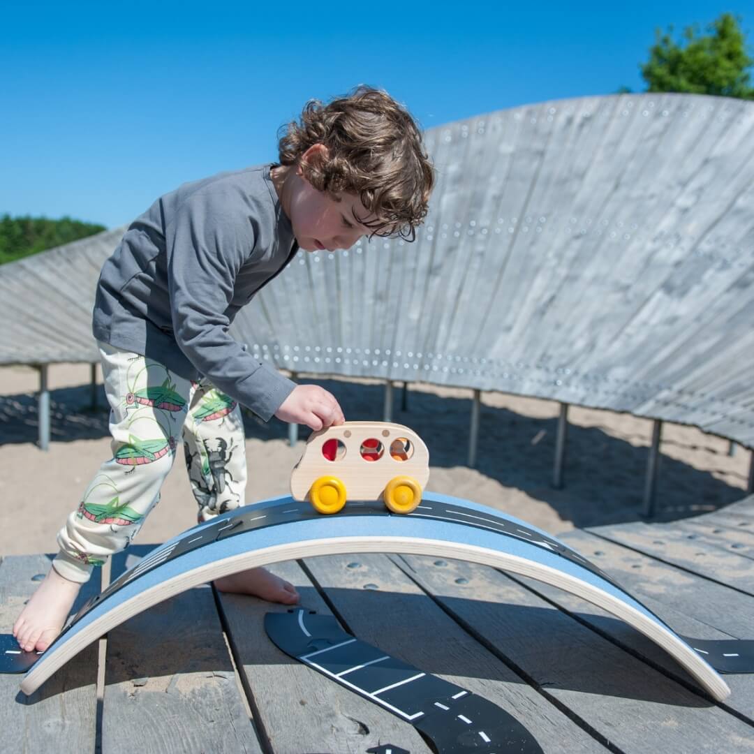 Child using Wobbel Board as bridge and tunnel for wooden vehicle play at Oskar's Wooden Ark in Australia