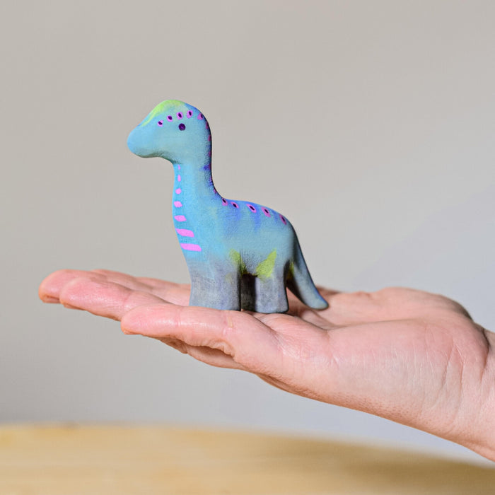 BumbuToys Handcrafted Wooden Baby Dinosaur Brontosaurus from Australia on an adult person's palm