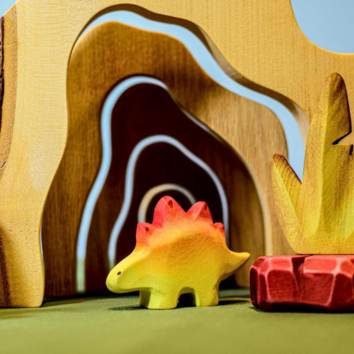 BumbuToys Handcrafted Wooden Dinosaur Baby Stegosaurus from Australia in a small-world play setting