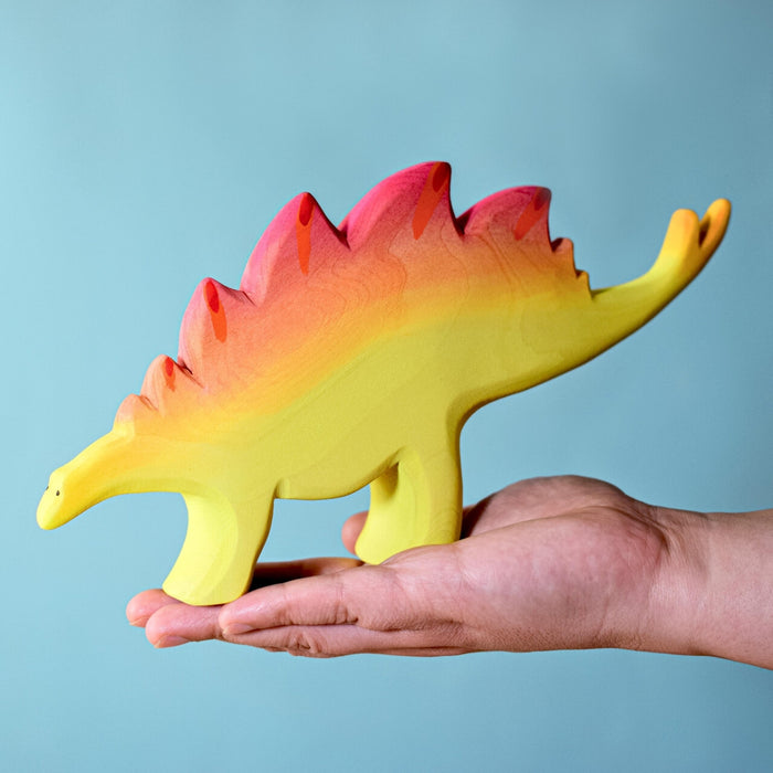 BumbuToys Handcrafted Wooden Dinosaur Stegosaurus Set Big from Australia on an adult person's hand