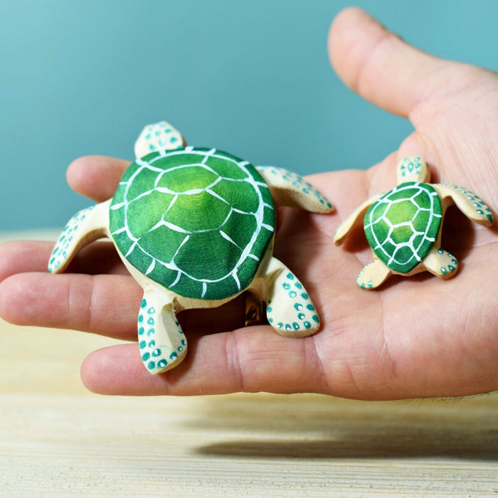 BumbuToys Handcrafted Wooden Turtles in Green from Australia on an adult person's hand