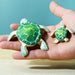 BumbuToys Handcrafted Wooden Turtle in Green from Australia on an adult person's hand
